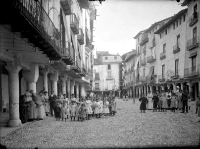 Grups de persones, la majoria infants, a la plaça major porxada de Barbastre