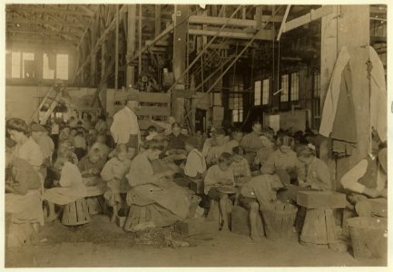 Interior of J. S. Farrand Packing Company, Baltimore, Md. Many tiny workers. Babies are held on laps of workers, or stowed away in empty boxes. LOC nclc.05423