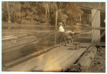 Hard work and dangerous. This 'river-boy' Lyman Frugia, poles the heavy logs into the incline that takes them to the mill. It is not only hard work, but he is exposed to all kinds of LOC nclc.04915