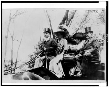 Harris Charles Fahnestock seated in carriage next to woman in plumed hat (possibly his wife) with another couple at the back of the carriage LCCN91483125