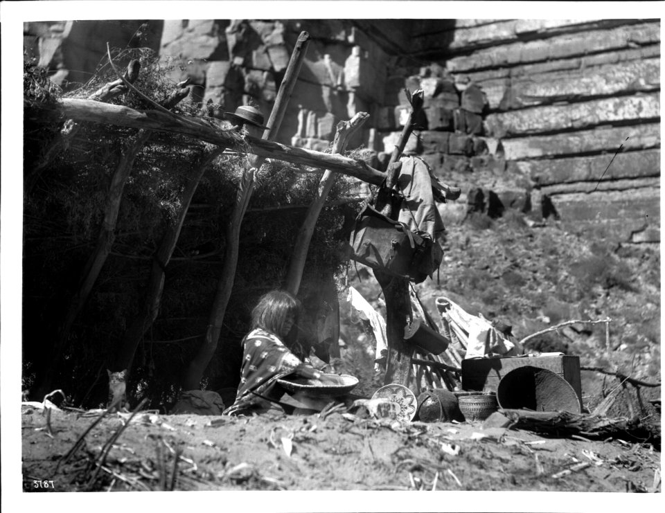 Havasupai Indian woman, Chick-a-pan-a-gie's wife, parching corn in a basket in front of her Hawa or dwelling, 1898 (CHS-3787)
