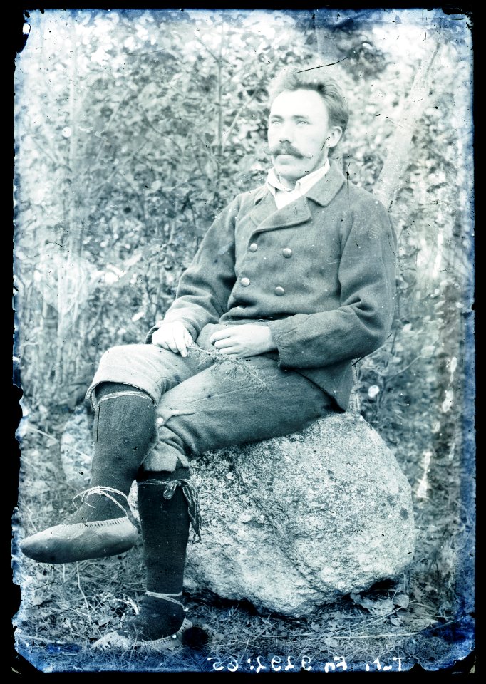 Heinrich Tiidermann - Rahvariides mees istumas kivi otsas