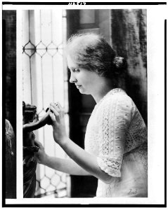 Helen Keller, half-length portrait, facing left, touching statue LCCN94515624