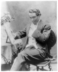 Henry B. Walthall, three-quarters length, seated on chair, facing left, hand under chin, looking at picture LCCN2005679807