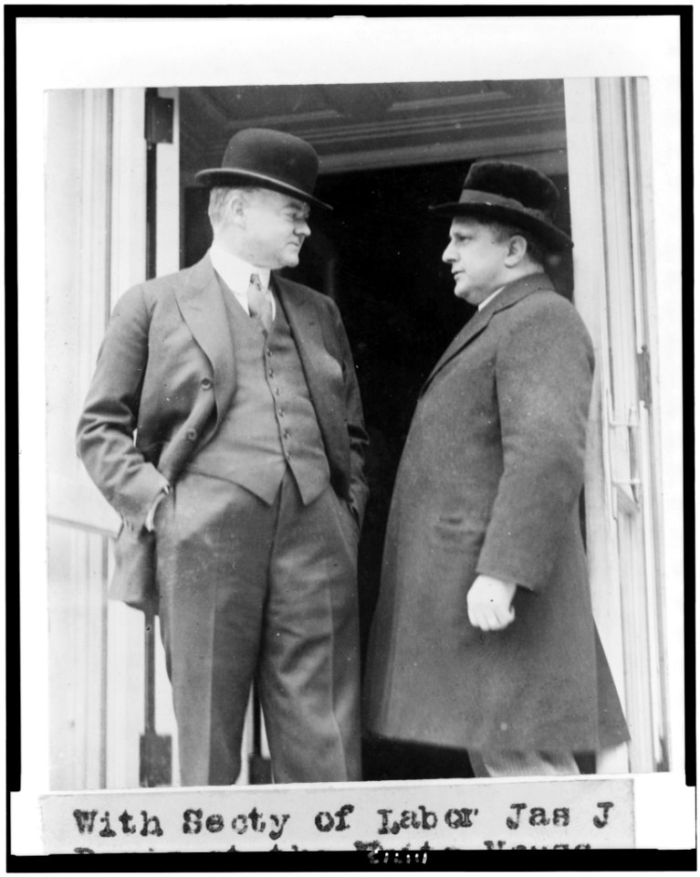 Herbert Hoover and Secretary of Labor James J. Davis, three-quarter length portrait, standing in doorway of the White House, facing each other LCCN94509137