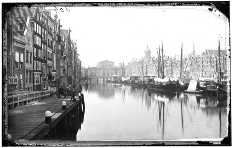 Het Damrak gezien in zuidelijke richting naar de Papenbrug en de achterzijde van de Beurs van Zocher, met links de achterzijde van de Warmoesstraat photo