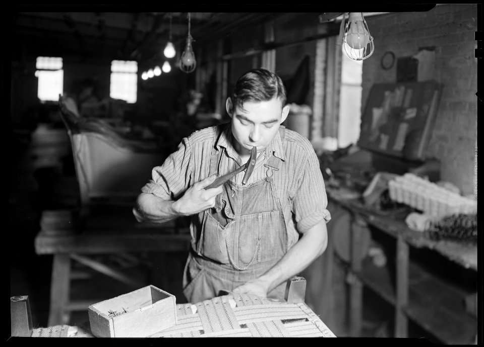High Point, North Carolina - Upholstering. Tomlinson Chair Manufacturing Co. Apply webbing to the frame - chair - NARA - 518476