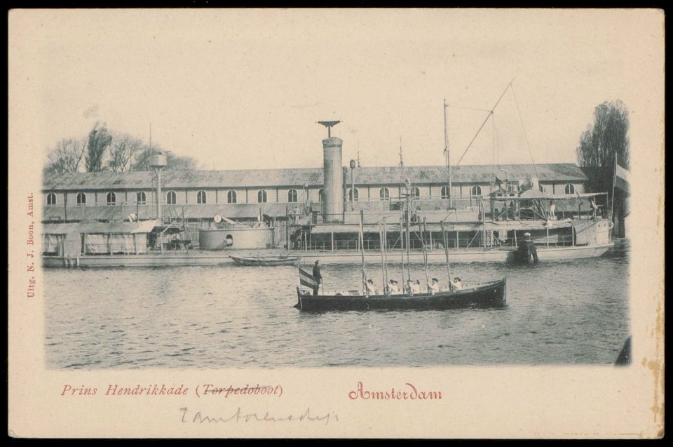 Het Oosterdok met een oorlogsschip voorzien van zwaar geschut voor de wal bij het Marine-etablissement