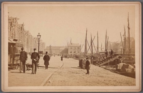 Het oude Damrak bij de voormalige Papenbrug met een wagen van de in 1876 geopende paardentramlijn Dam-Prins Hendrikkade en op de achtergrond de Korenbeurs