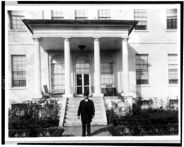 Hiram W. Johnson, full-length portrait, standing outside of mansion, facing left LCCN92508831