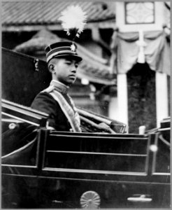 Hirohito, Emperor of Japan, half-length portrait, facing right, seated in carriage with chrysanthemum emblem on the door LCCN89714085