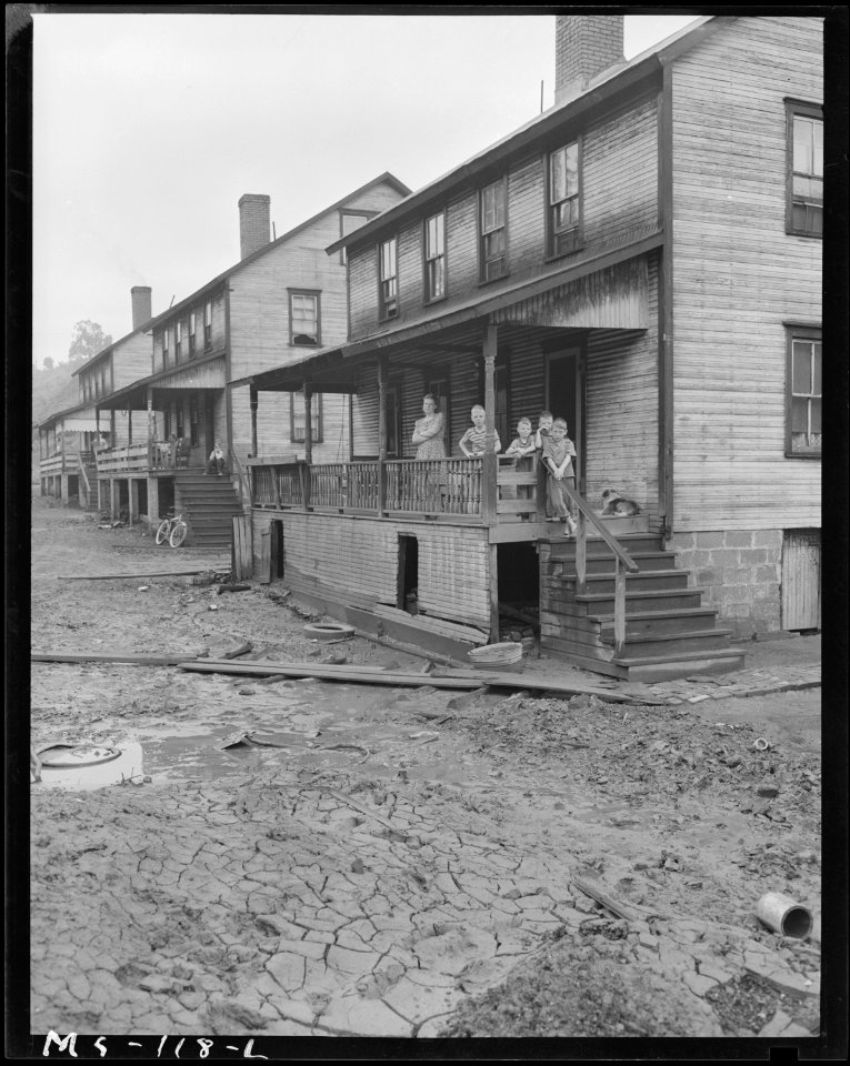 Home and family of Monzel Cox in company housing project. In foreground of picture is caked mud left by flood of... - NARA - 540284