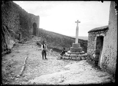Home i dona a la creu de davant la porta del castell d'Alquézar