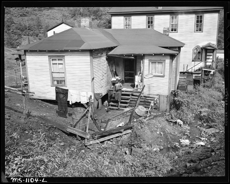 Home of miner who lives in company housing project. Church in background. Note garbage littered stream in foreground.... - NARA - 540669