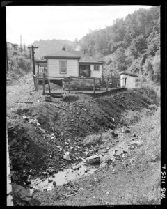 Home of miner who lives in company housing project. Note garbage littered stream in foreground. Mullens Smokeless... - NARA - 540670