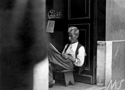 Homem lendo jornal na porta de estabelecimento comercial - Vincenzo Pastore photo