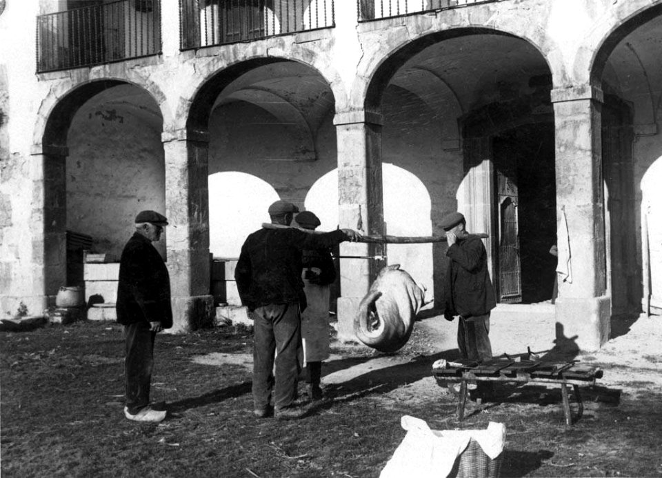 Homes fent la pesada romana del porc al Cavaller de Vidrà