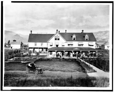 Hotel Sierra, Loyalton, California, with people standing on porch, people in automobile in foreground, and mountains in background LCCN94505317