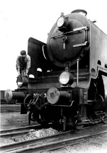 HUA-151483-Afbeelding van de voorzijde van de stoomlocomotief nr. 3915 (serie 3900) van de N.S. met op de locomotief personeel dat de lampen poetst