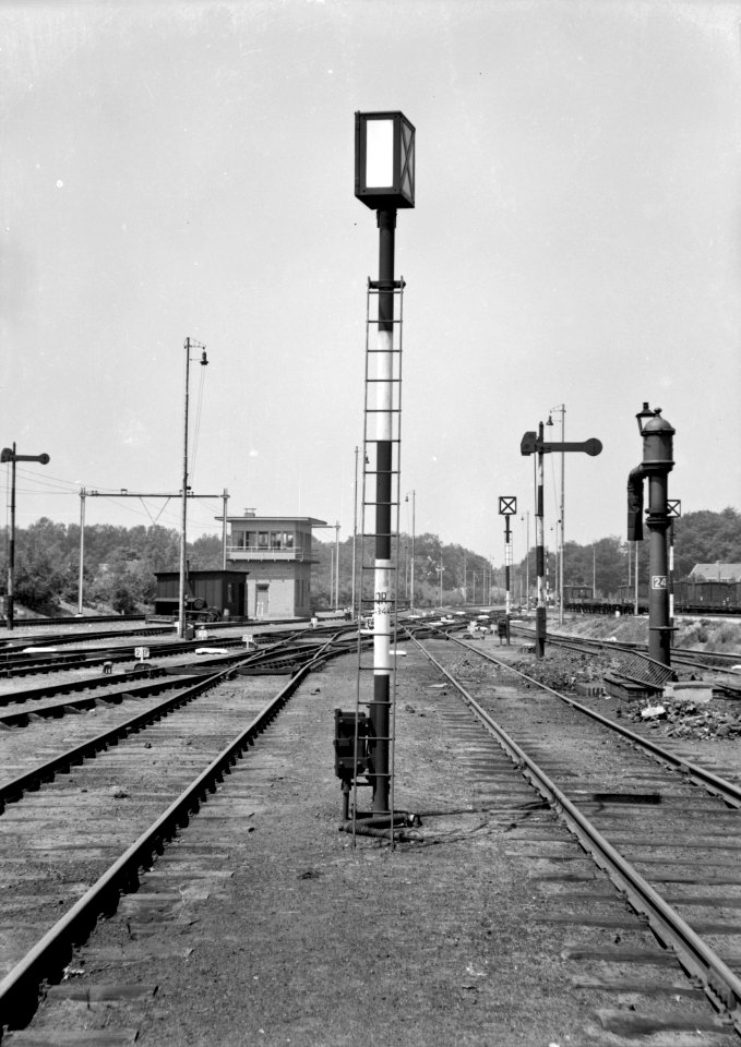 HUA-153922-Afbeelding van een rangeerpaallantaarn (rouwbrief) van de N.S. te Amersfoort met rechts een armsein en een waterkolom en links op de achtergrond het seinhuis Post VII aan de westzijde van het emplac