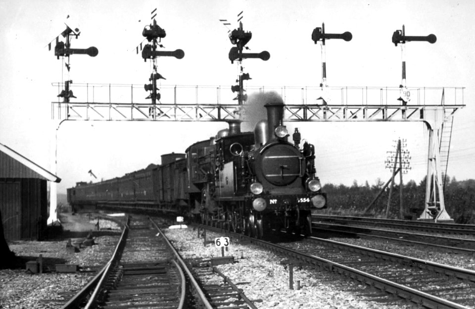 HUA-151319-Afbeelding van de stoomlocomotief nr. 5554 (serie 5500) en een stoomlocomotief uit de serie 3600 van de N.S.met rijtuigen onder de seinbrug te Naarden-Bussum
