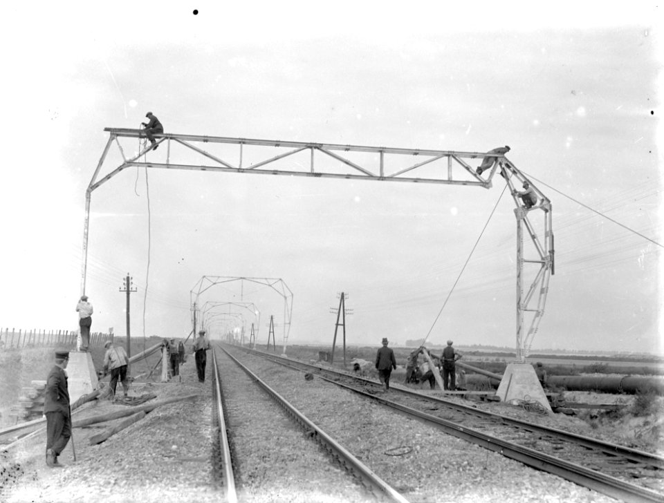 HUA-160498-Afbeelding van de plaatsing van een a-symetrisch bovenleidingsportaal tijdens de electrificatie van de spoorlijn Schiedam - Hoek van Holland