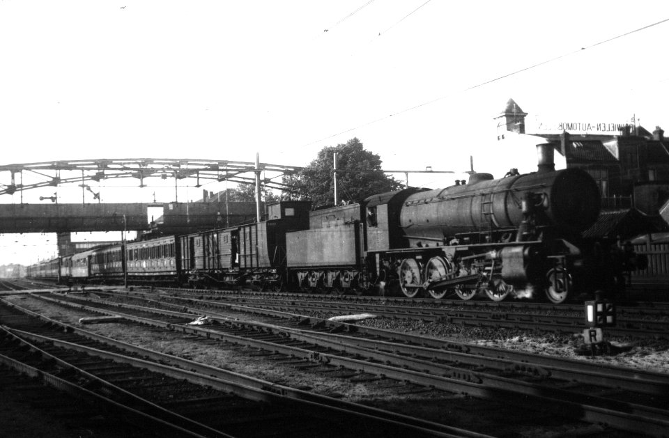 HUA-160569-Afbeelding van een stoomlocomotief uit de serie 4300-4400-4500 (Austerities, ex War Department) van de N.S. met een reizigerstrein te Hilversum