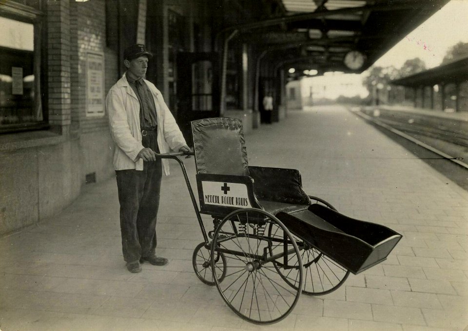 HUA-163188-Afbeelding van een perronassistent met een rolstoel van het Nederlandsche Roode Kruis op het perron van het N.S.-station Naarden-Bussum te Bussum