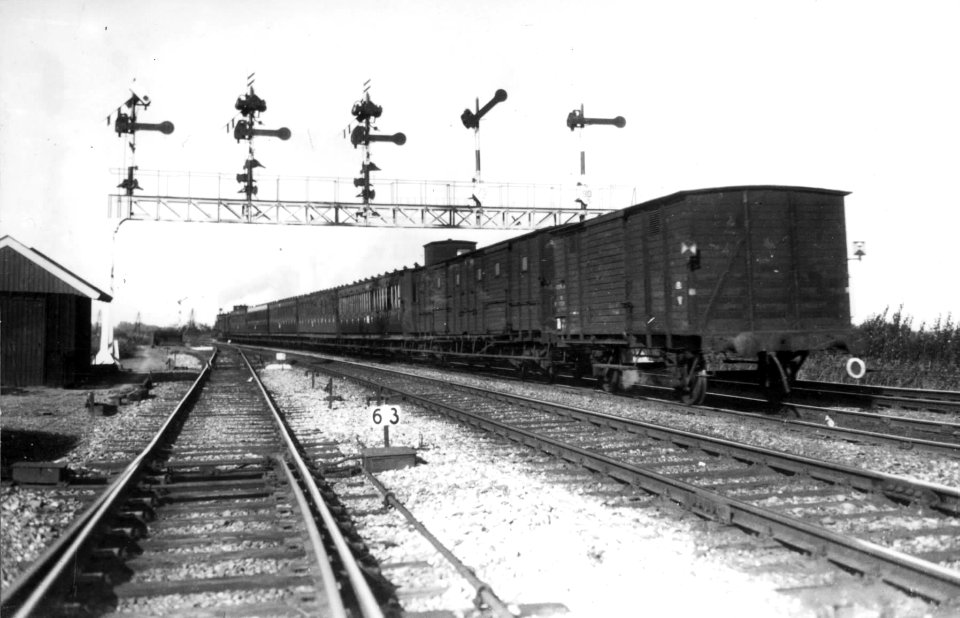 HUA-151322-Afbeelding van een stoomtrein (met rijtuigen en goederenwagens) onder de seinbrug op het emplacement van station Naarden-Bussum te Bussum