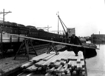 HUA-163240-Afbeelding van het overladen van hout van schip op trein bij de Parallelvaart bij het N.S.-station Zaandam te Zaandam