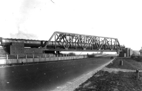 HUA-163327-Gezicht op het spoorviaduct over de Muiderstraatweg te Diemen met een passerende trein getrokken door een stoomlocomotief uit de serie 3700 3800 van d