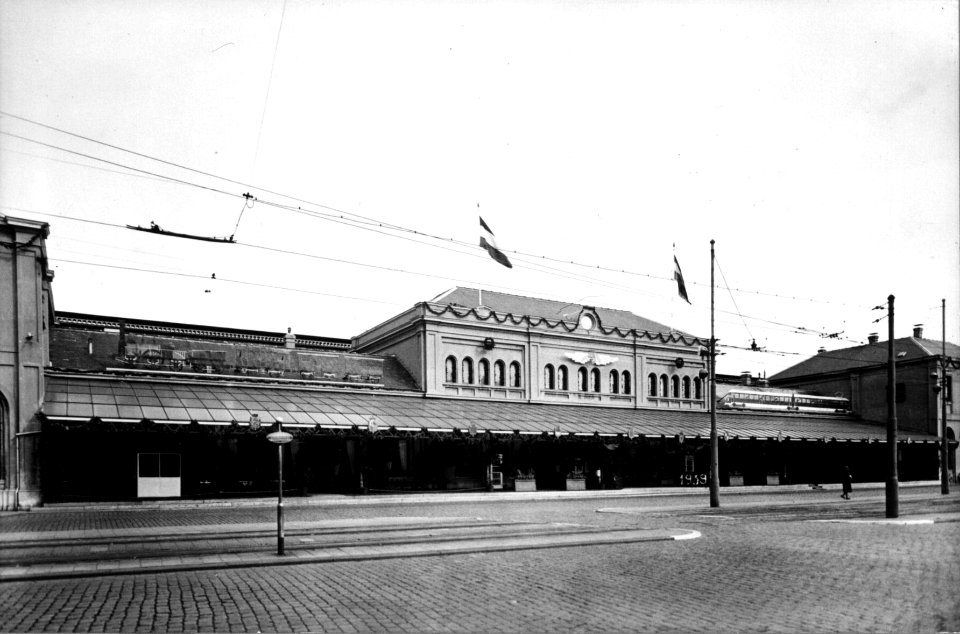 HUA-153796-Gezicht op de versierde voorgevel van het station van de Staats Spoorwegen te Den Haag ter gelegenheid van het 100-jarig bestaan van de N.S.