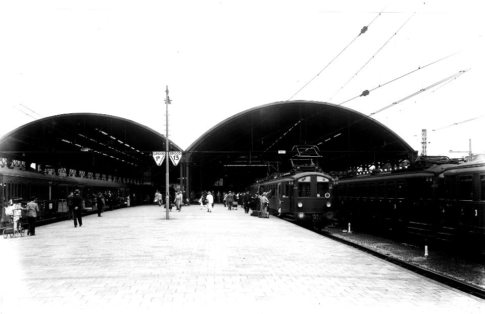 HUA-163382-Gezicht op het perron met perronkappen van het N.S.-station Rotterdam D.P. te Rotterdam met instappende reizigers in een trein bestaande uit rijtuigen electrisch buffermaterieel (mat. 1924, blokkendo