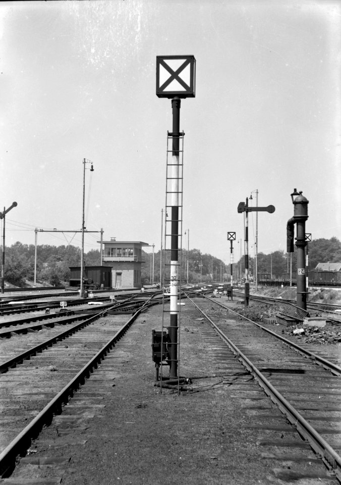 HUA-153921-Afbeelding van een rangeerpaallantaarn (rouwbrief) van de N.S. te Amersfoort met rechts een armsein en een waterkolom en links op de achtergrond het seinhuis Post VII aan de westzijde van het emplac