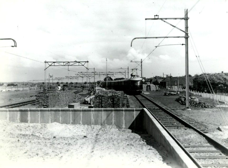 HUA-163537-Gezicht op de werkzaamheden ten behoeve van het herstel van oorlogsschade aan spoorbaan en perron van het N.S.-station Zandvoort te Zandvoort aan Zee. Op de achtergrond een electrisch treinstel mat. 1
