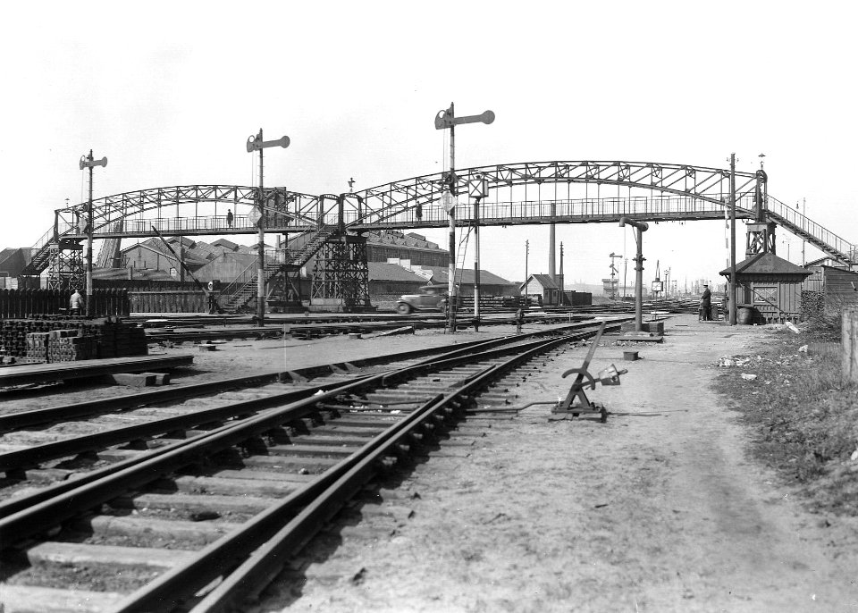 HUA-163648-Gezicht op de voetbrug en de spoorwegovergang in de Handelskade bij het goederenemplacement Rietlanden te Amsterdam. N.B. De afbeelding maakt deel uit van een serie foto's met betrekking tot de Spoorw
