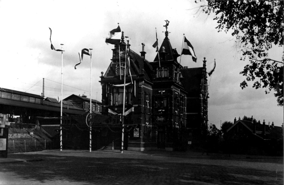 HUA-153798-Gezicht op de versierde voorgevel van het N.S-station Schiedam te Schiedam ter gelegenheid van het 100-jarig bestaan van de N.S.