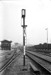 HUA-153919-Afbeelding van een rangeerpaallantaarn (rouwbrief) van de N.S. te Utrecht, in de stand rangeren toegestaan. Op de achtergrond het seinhuis H en de hoge post (Post R)
