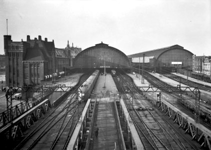 HUA-154584-Gezicht op de perrons en de sporen aan de oostzijde van het NS station Amsterdam CS te Amsterdam met op de achtergrond de perronkappen en het stations