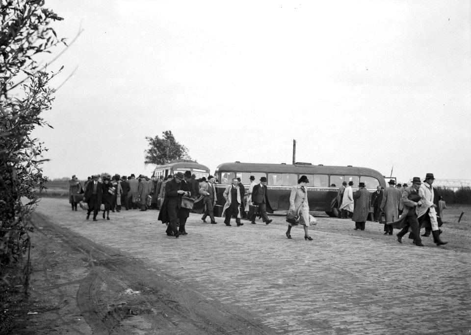 HUA-166029-Afbeelding van treinreizigers die per bus van het N.S.-station Waardenburg naar de pont over de Waal gebracht zijn, in verband met de in mei 1940 opgeblazen spoorbrug tussen Waardenburg en Zaltbommel