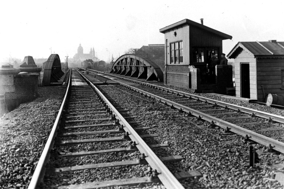 HUA-160502-Gezicht op de spoorbrug over de Oosterdoksluis te Amsterdam met rechts de brugpost NB De brug werd in mei 1936 gesloopt in het kader van de spoorwegwe