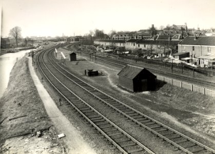 HUA-167120-Gezicht vanaf de Jeremiebrug op de nog lage spoorlijnen uit Arnhem en 's-Hertogenbosch (voorgrond), met links de Kruisvaart, rechts de achterzijdes van de huizen aan de Vaartsestraat en op de achtergr