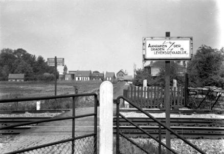 HUA-167620-Gezicht op een onbewaakte spoorwegovergang in een zijweggetje van de Westkanaaldijk te Maarssen (bij km. paal 28.9), met een bord Aanraken der draden is levensgevaarlijk