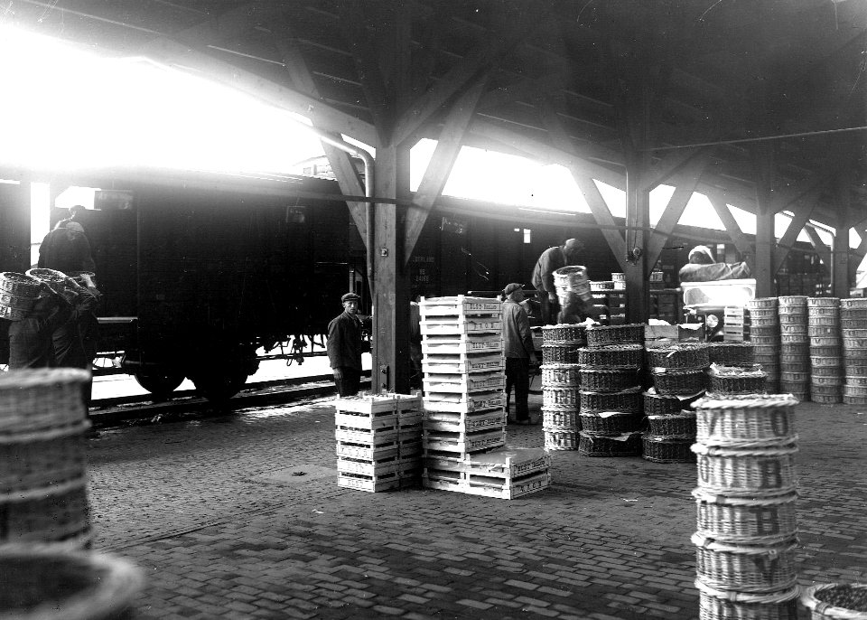 HUA-163381-Afbeelding van het overladen van kersen in de goederenloods van de N.S. te Elst