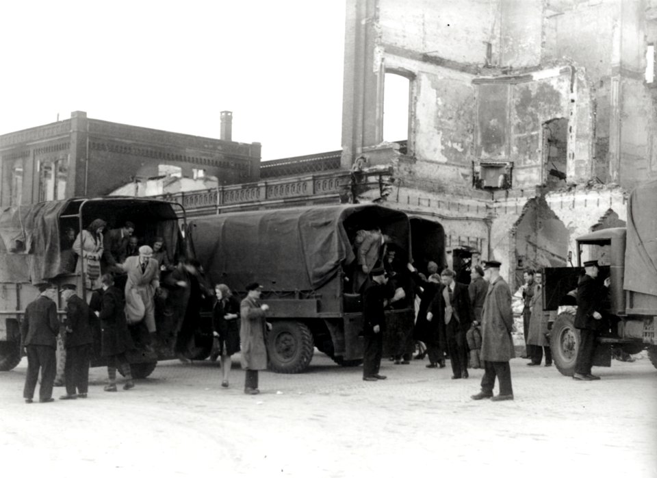 HUA-168056-Afbeelding van vrachtauto's van het Canadese leger die ingezet worden door de N.S. als vervangend vervoer voor treintreizigers op het Stationsplein te Arnhem. Op de achtergrond het tijdens de oorlog v
