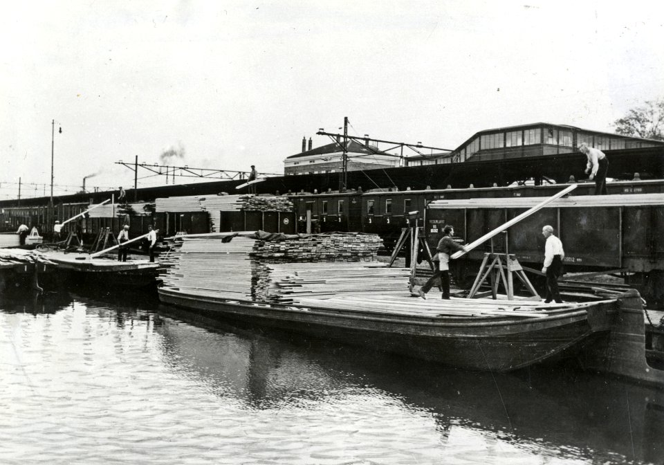 HUA-170961-Afbeelding van de overslag van hout van schip naar trein in de haven bij het N.S.-station Zaandam