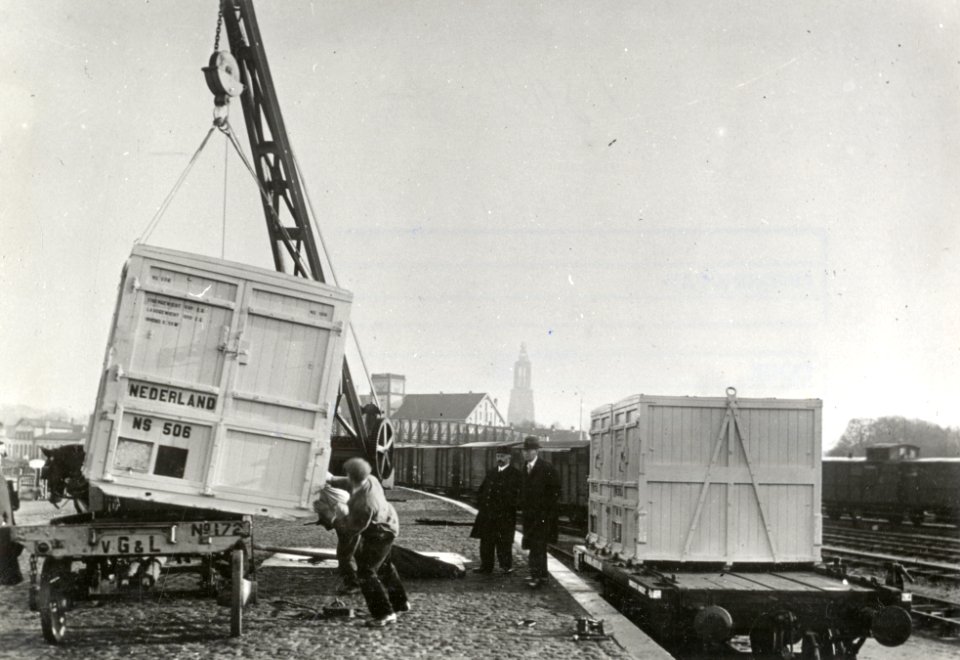 HUA-169735-Afbeelding van het overladen van een laadkist van de N.S. van spoor naar paard en wagen (of andersom) met behulp van een takel op de laad- en losplaats van het N.S.-station Amersfoort