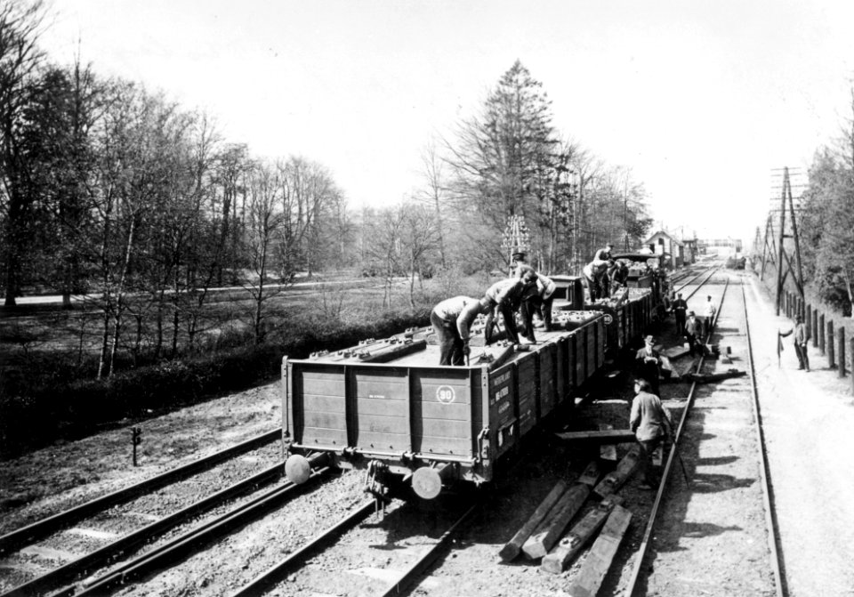 HUA-168947-Afbeelding van het lossen van dwarsliggers op de spoorlijn nabij het N.S.-station Driebergen te Driebergen-Rijsenburg. N.B. De stationsnaam Driebergen is in 1948 gewijzigd in Driebergen-Zeist