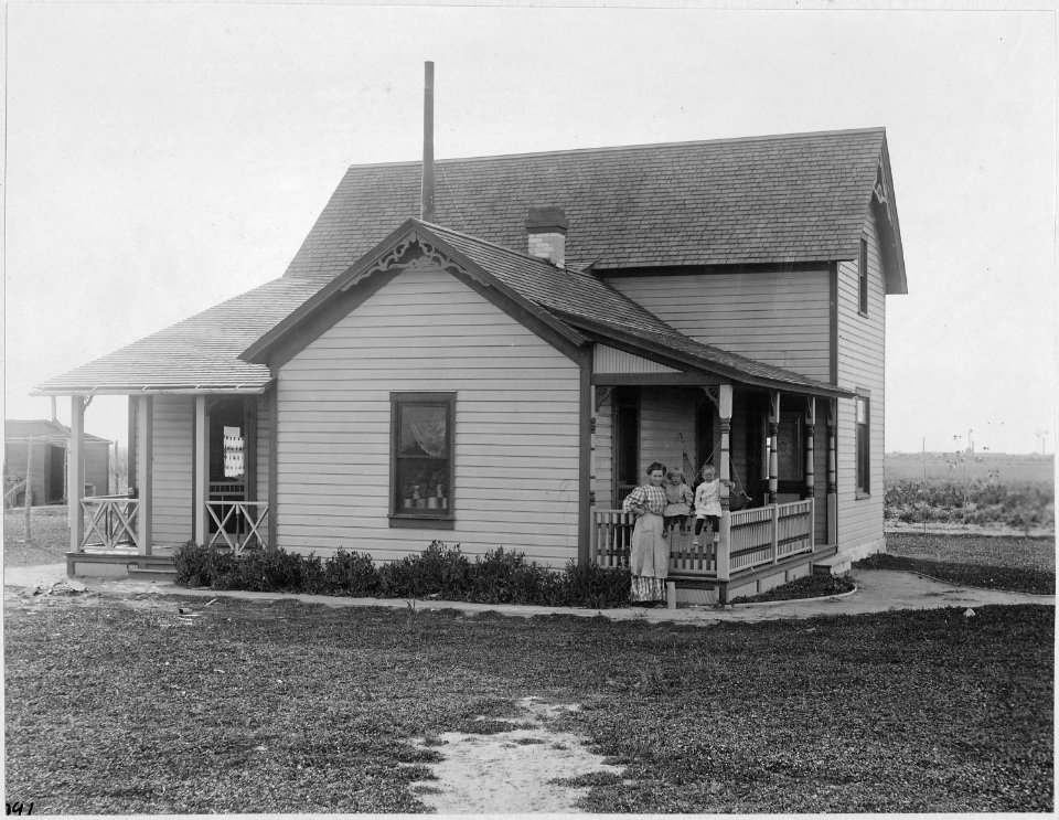 Idaho. Minidoka. Farm house and lawn on B. E. Smith ranch. (Woman and two children at the front of the house.) - NARA - 531557