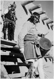 Indian descending wooden stairs with drum, another in background looking on, Dance, San Ildefonso Pueblo, New Mexico, 1 - NARA - 519977